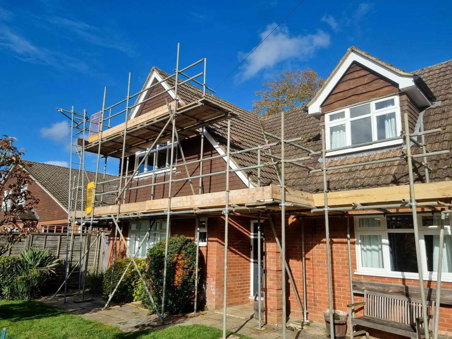 A house under construction with scaffolding on the roof.